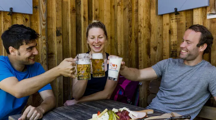 Auf der Hütte: Drei Personen stoßen mit Bierkrügen an | © DAV/Hans Herbig